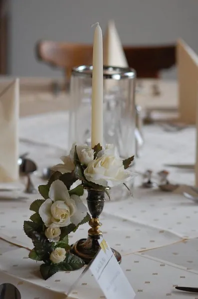 Kerze mit weißen Rosen auf einem festlich gedeckten Tisch